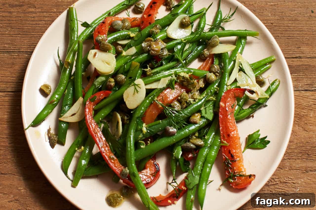 Fresh green bean salad with red peppers, capers and herbs on a plate.
