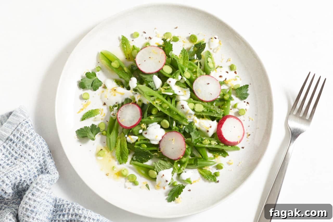 A plate of sugar snap pea salad topped with radishes and yogurt.