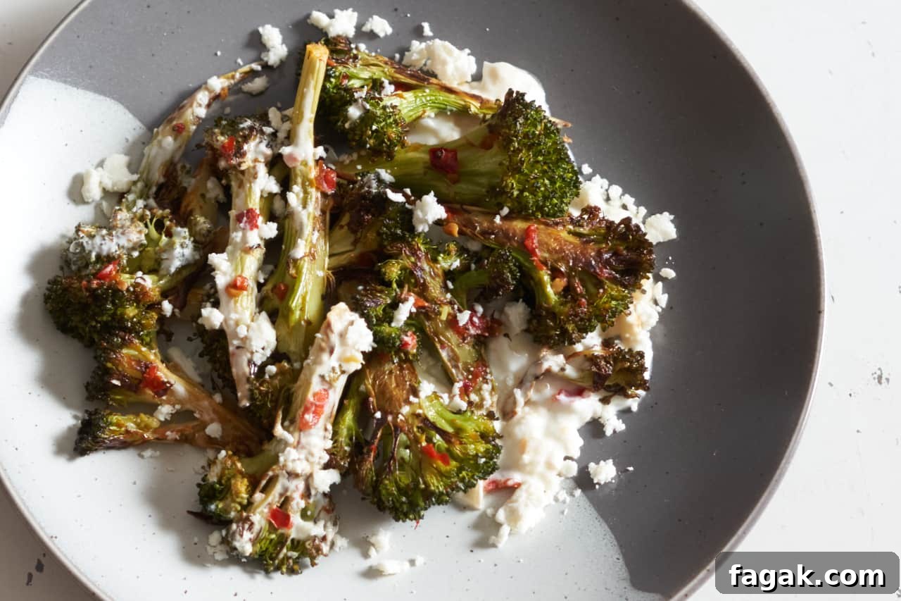 Charred broccoli with Calabrian chili paste on a grey and white plate.