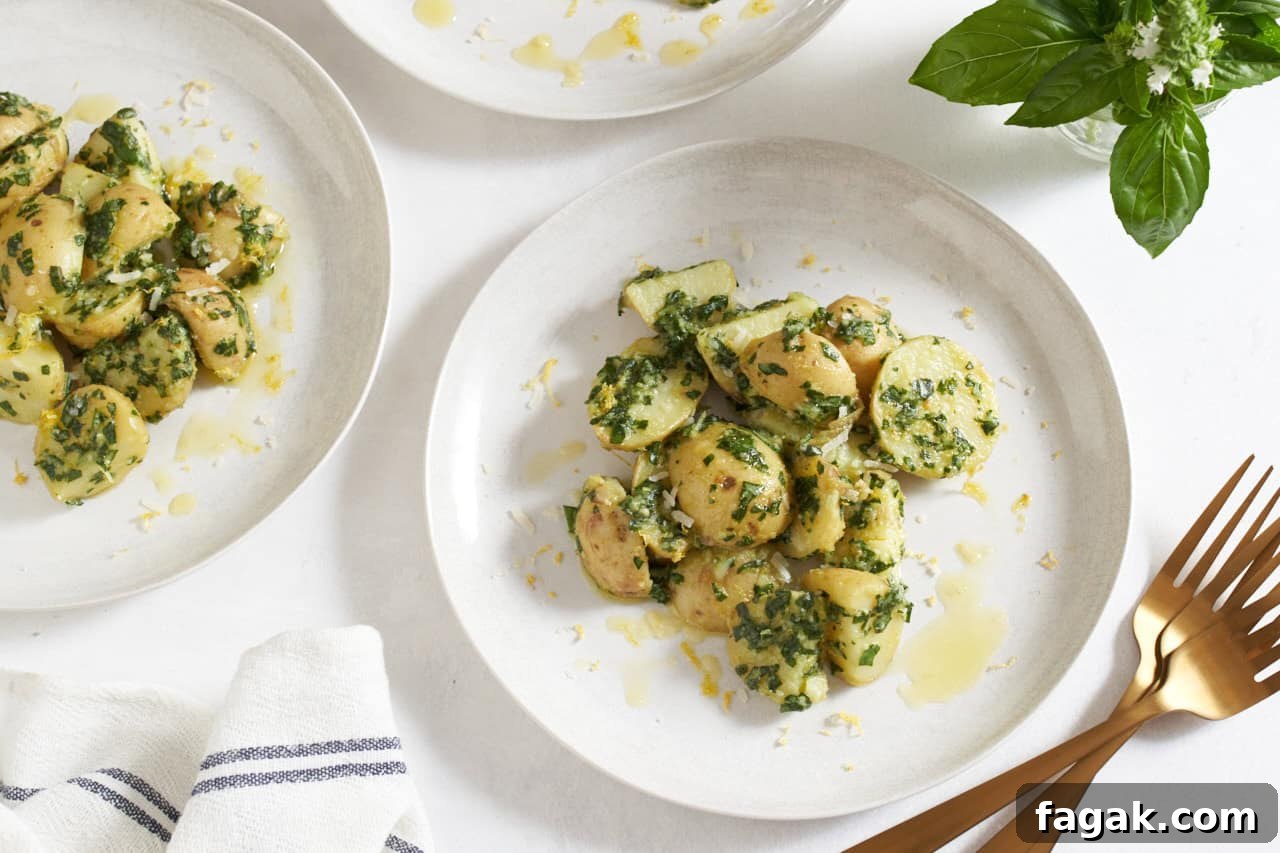 Two white plates with pesto potato salad, a jar of fresh basil is in the upper right.
