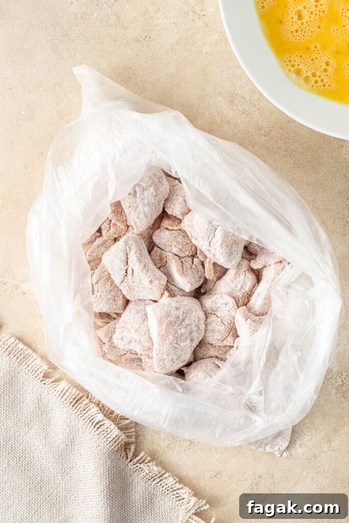 Tossing the chicken pieces in the cornflour mixture.