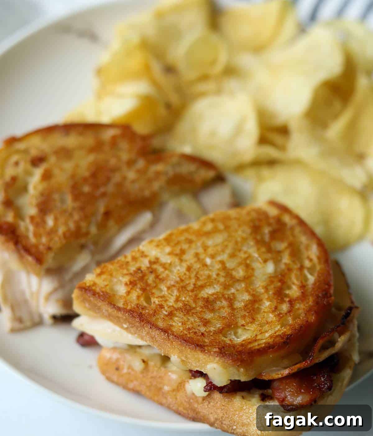 Crispy Bacon Turkey Melt with Cheddar and Garlic Aioli 8 Turkey bacon melt on plate sliced in half.