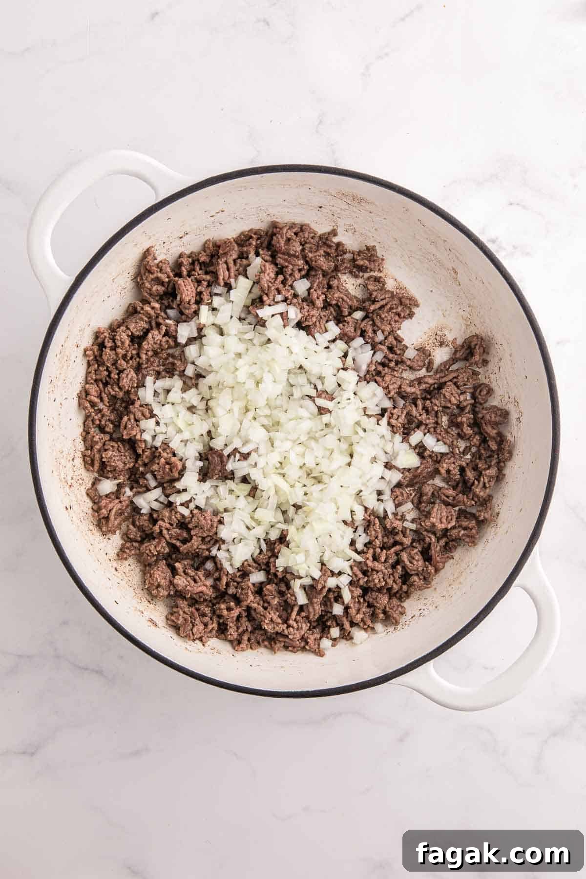 Ground beef browning in a large white pot topped with finely diced onion. The image shows the first cooking step for making baked beans with ground beef.