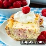 Raspberry Cheesecake Bar on a plate with whipped cream and fresh raspberries
