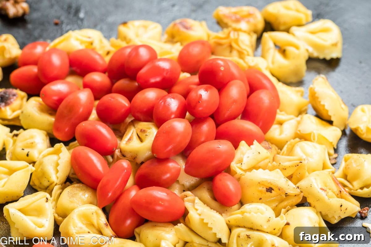 Topping the tortellini pasta with cherry tomatoes on the flat top griddle