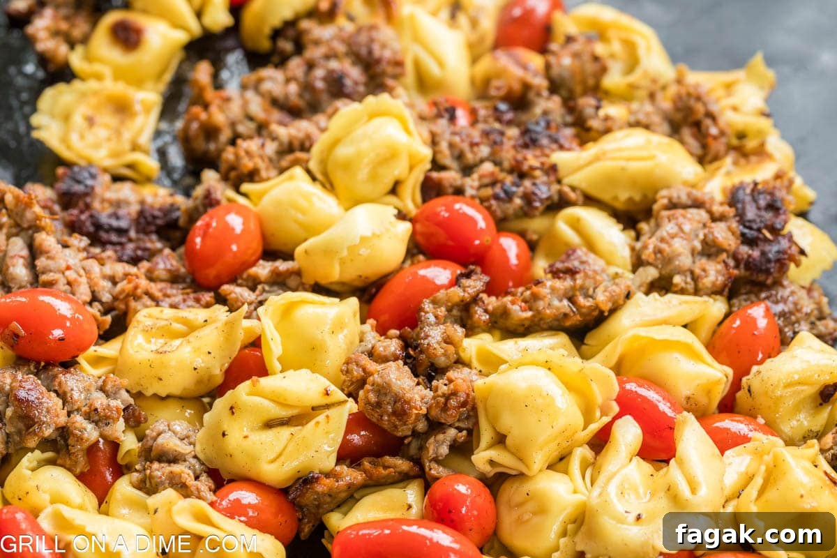 Mixing the cooked Italian Sausage with the tortellini pasta and cherry tomatoes