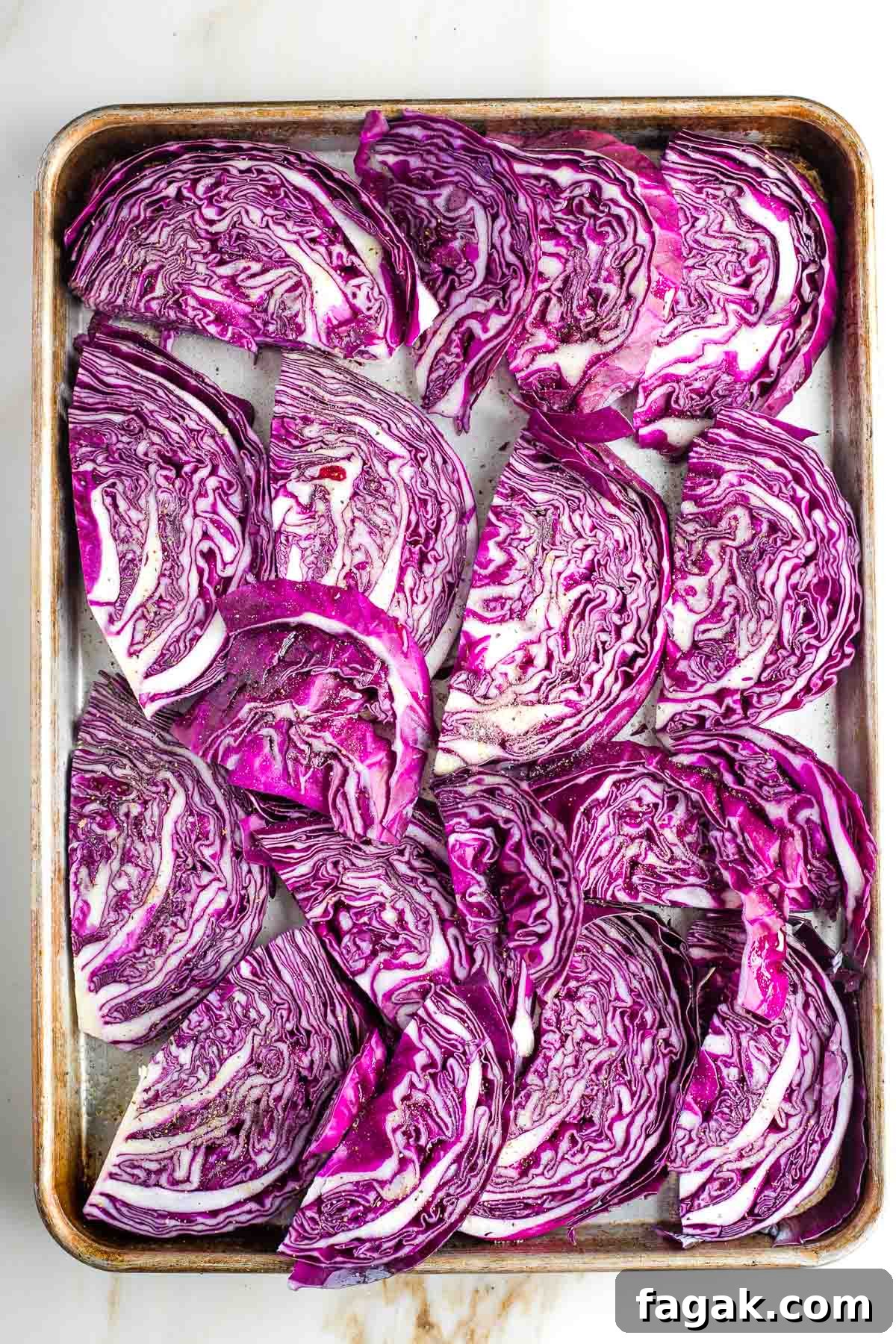 Crispy Oven-Roasted Red Cabbage with Balsamic Glaze 7 Red cabbage wedges on a large rimmed baking tray in a single layer.