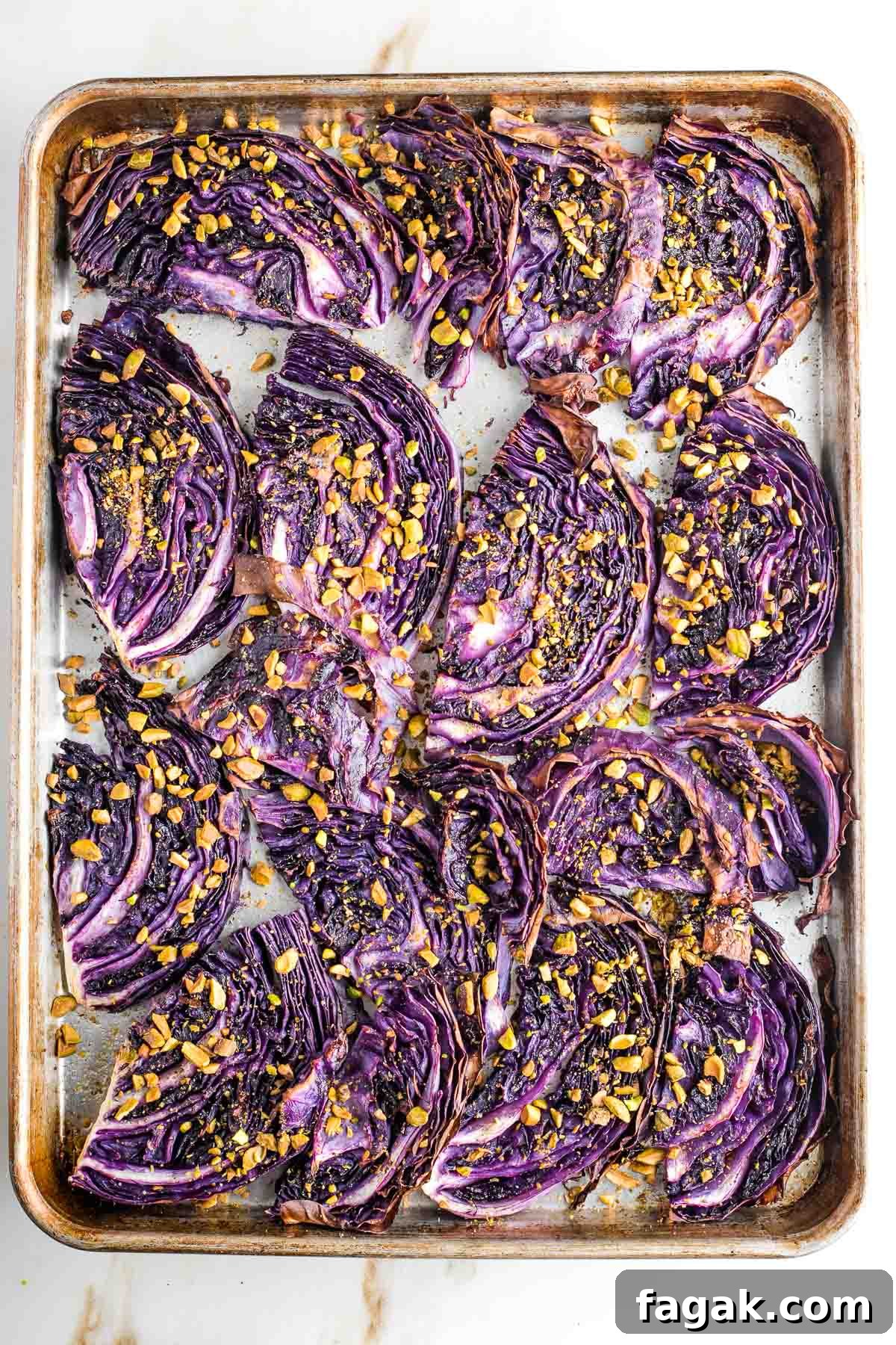 Crispy Oven-Roasted Red Cabbage with Balsamic Glaze 9 Roasted cabbage steaks on a baking tray with chopped pistachios on top.