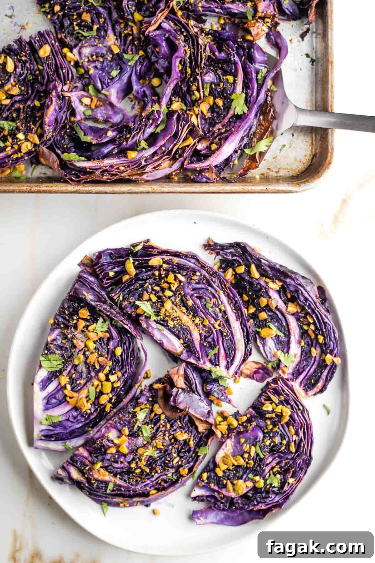 Crispy Oven-Roasted Red Cabbage with Balsamic Glaze 10 Serving from a tray of roasted cabbage steaks with chopped pistachios, onto a platter.