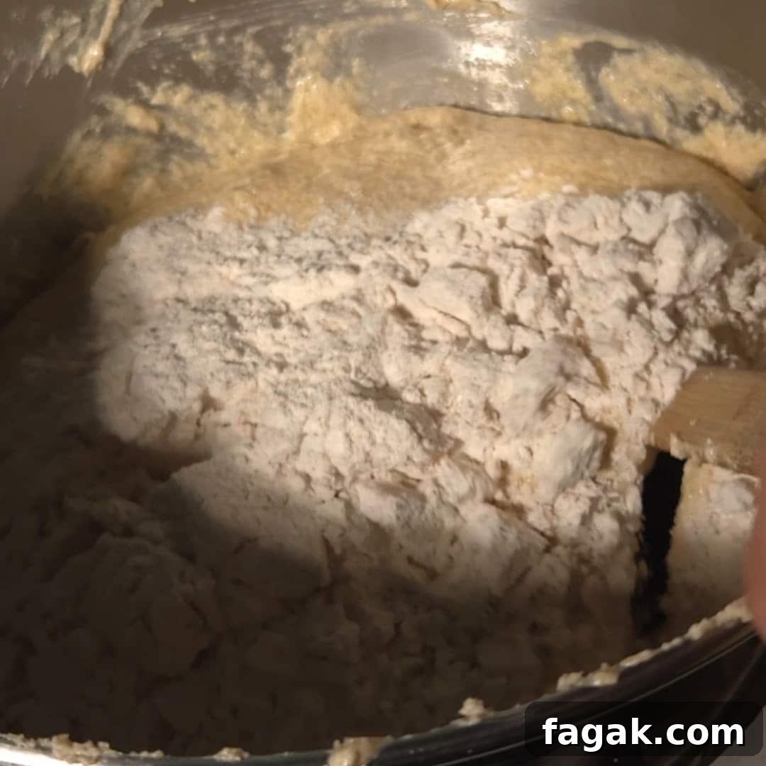 A mixing bowl filled with flour and chai spices being incorporated into the cake batter, capturing the process of creating the bundt spice cake.