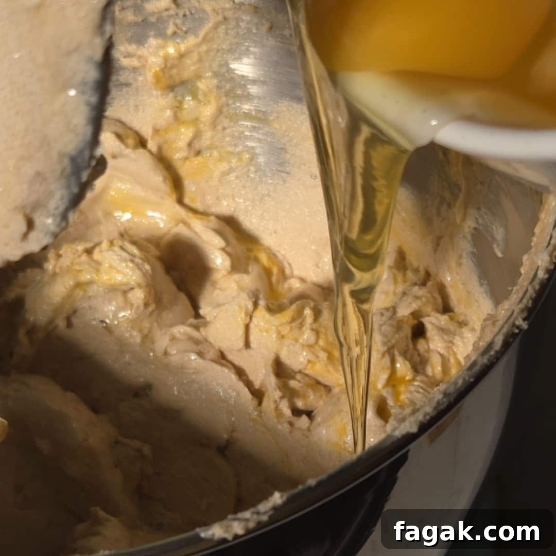 A stream of wet ingredients, including eggs, being poured into the chai spice cake batter, ready to be mixed.