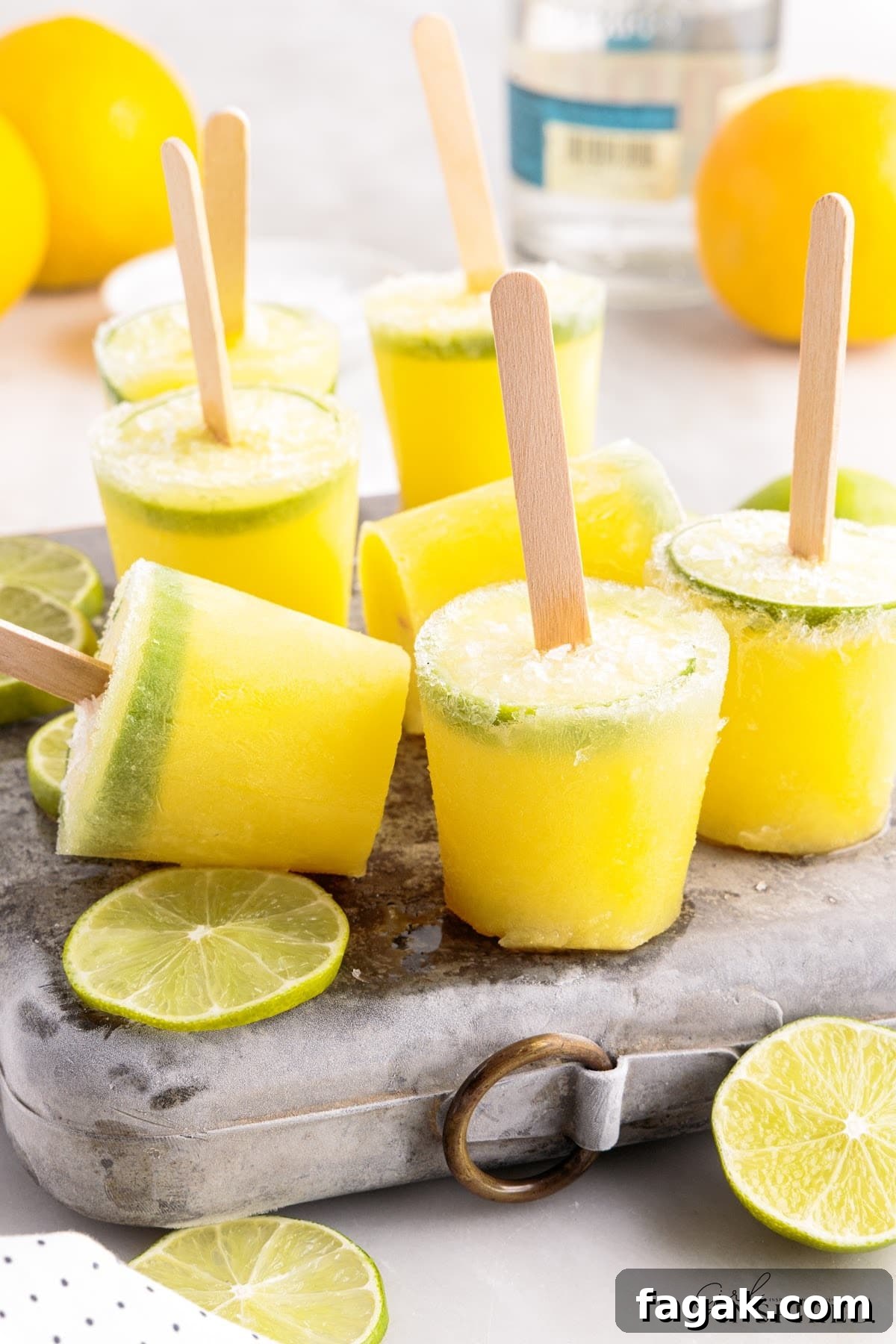 Margarita Popsicles standing on metal ice pack next to fresh lime wheels.