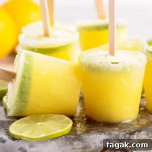 Margarita Popsicles standing on metal ice pack next to fresh lime wheels.