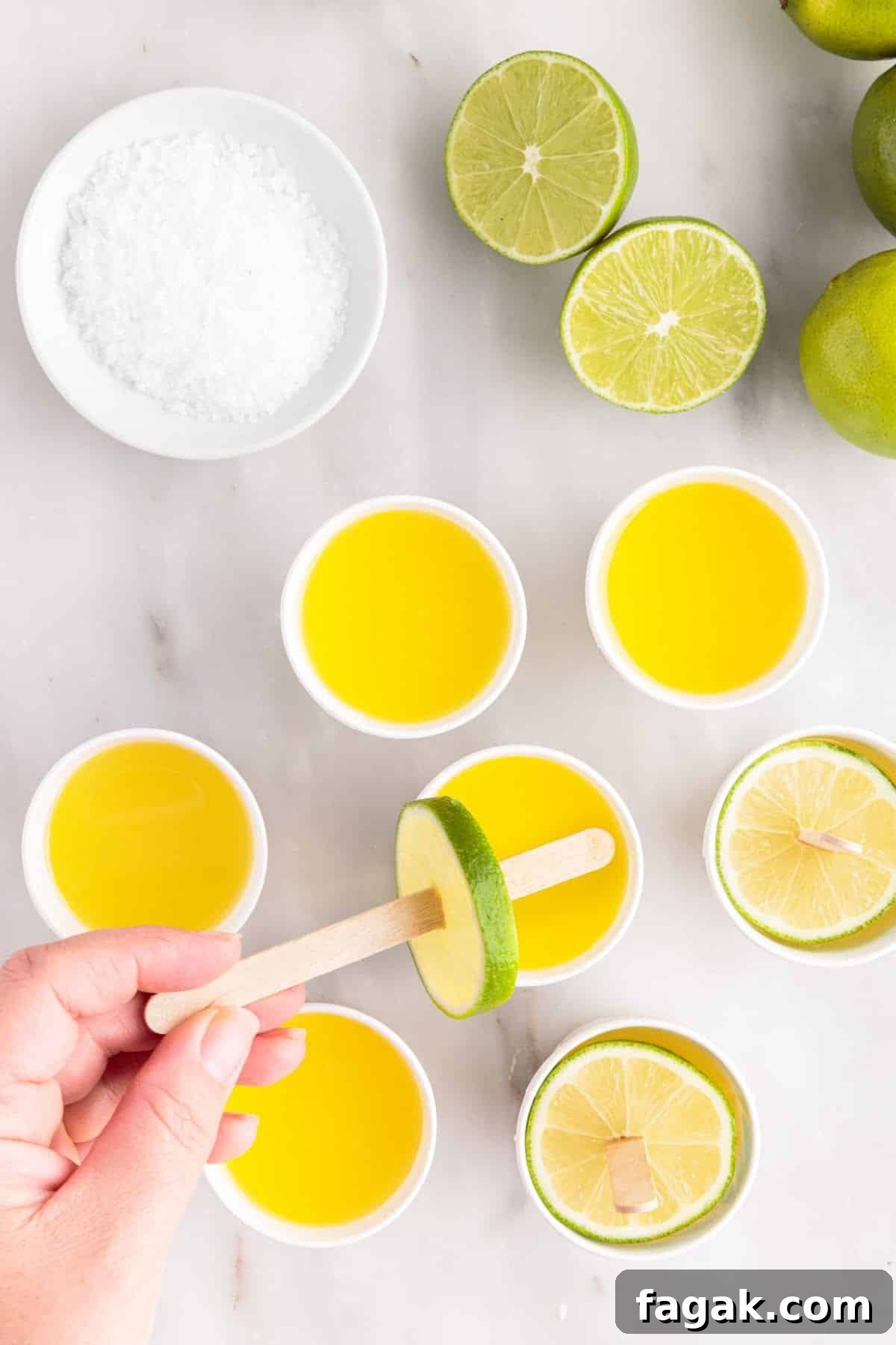 Placing popsicle stick pierced through a lime wheel into the Dixie cup filled with margarita mix.