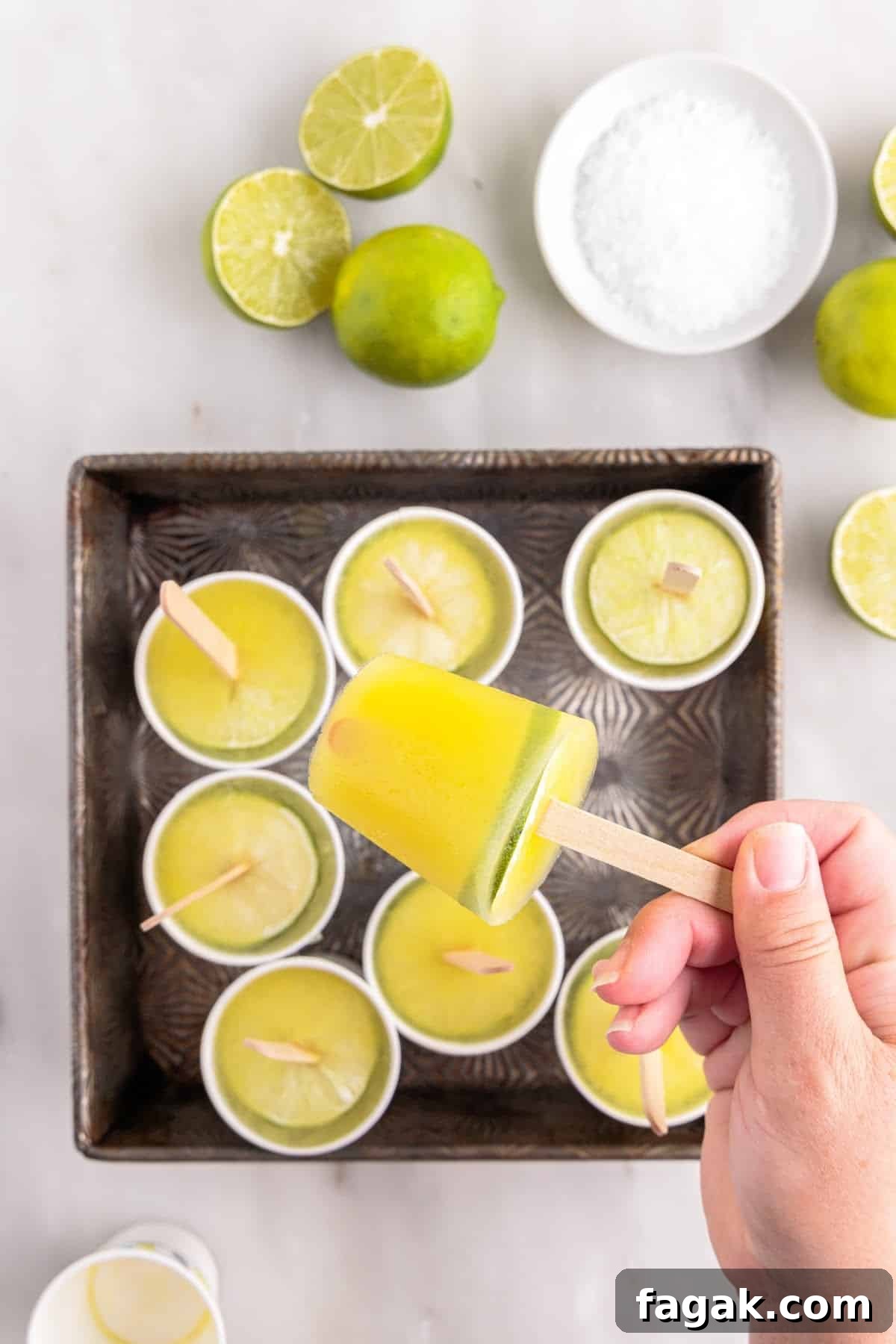 Holding a frozen margarita popsicle removed from Dixie cup over the pan of other popsicles.