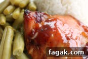 A white plate with a serving of green beans, white rice, and a sweet and sour chicken thigh.