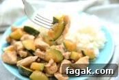Teriyaki Garlic Chicken Stir Fry on a blue plate with rice and a fork is taking a bite