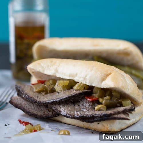 Italian beef sandwich on a soft roll, sitting on white parchment paper.