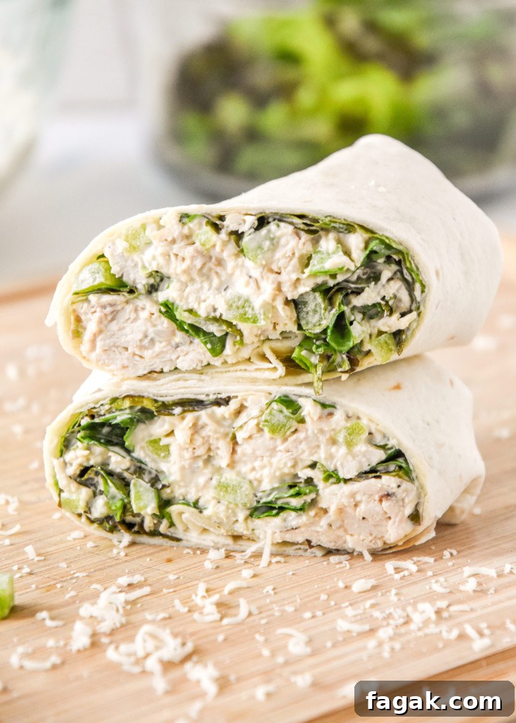 caesar chicken salad lunch wraps cut in half stacked on a cutting board.