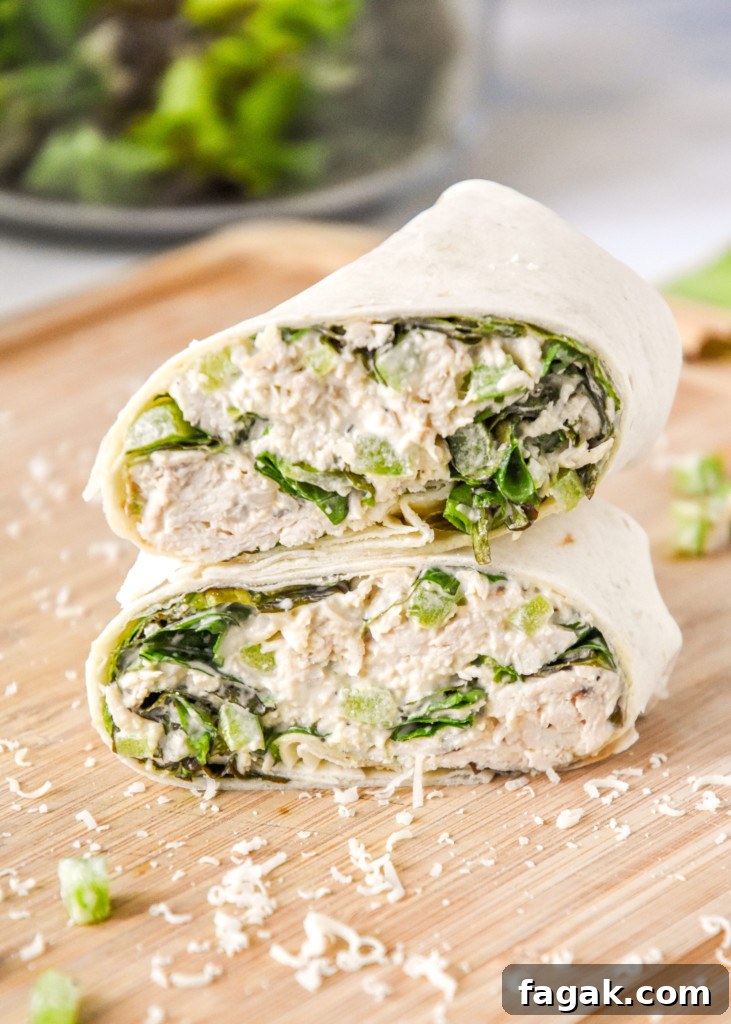 caesar chicken salad lunch wraps cut in half on a cutting board.