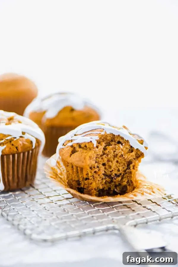 a gluten free sweet potato muffin with marshmallow glaze on top of a wire rack with a bite taken out