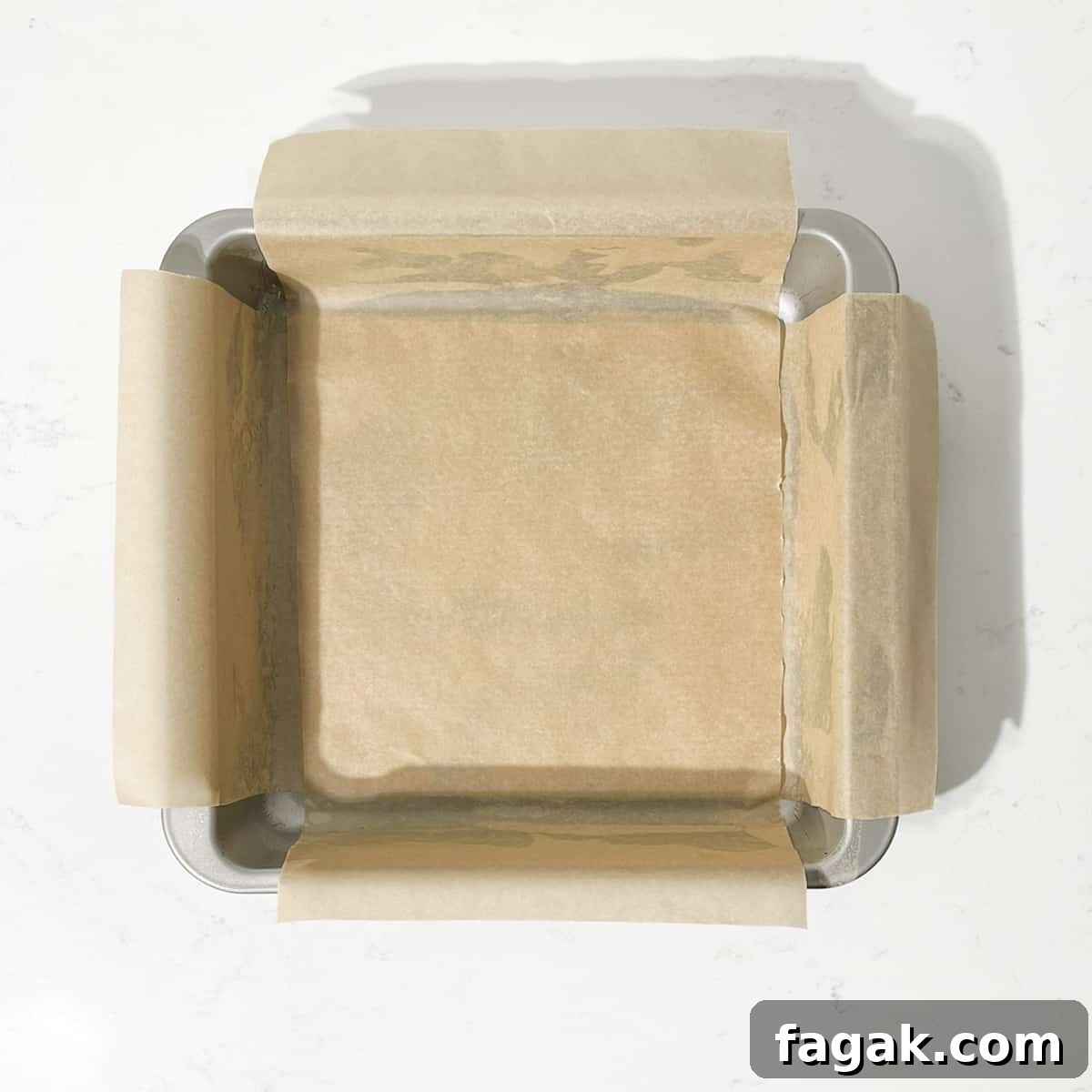 A square tin lined with baking paper.