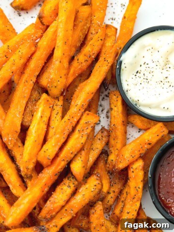 A plate of cooked sweet potato fries with side of ketchup and mayonnaise.