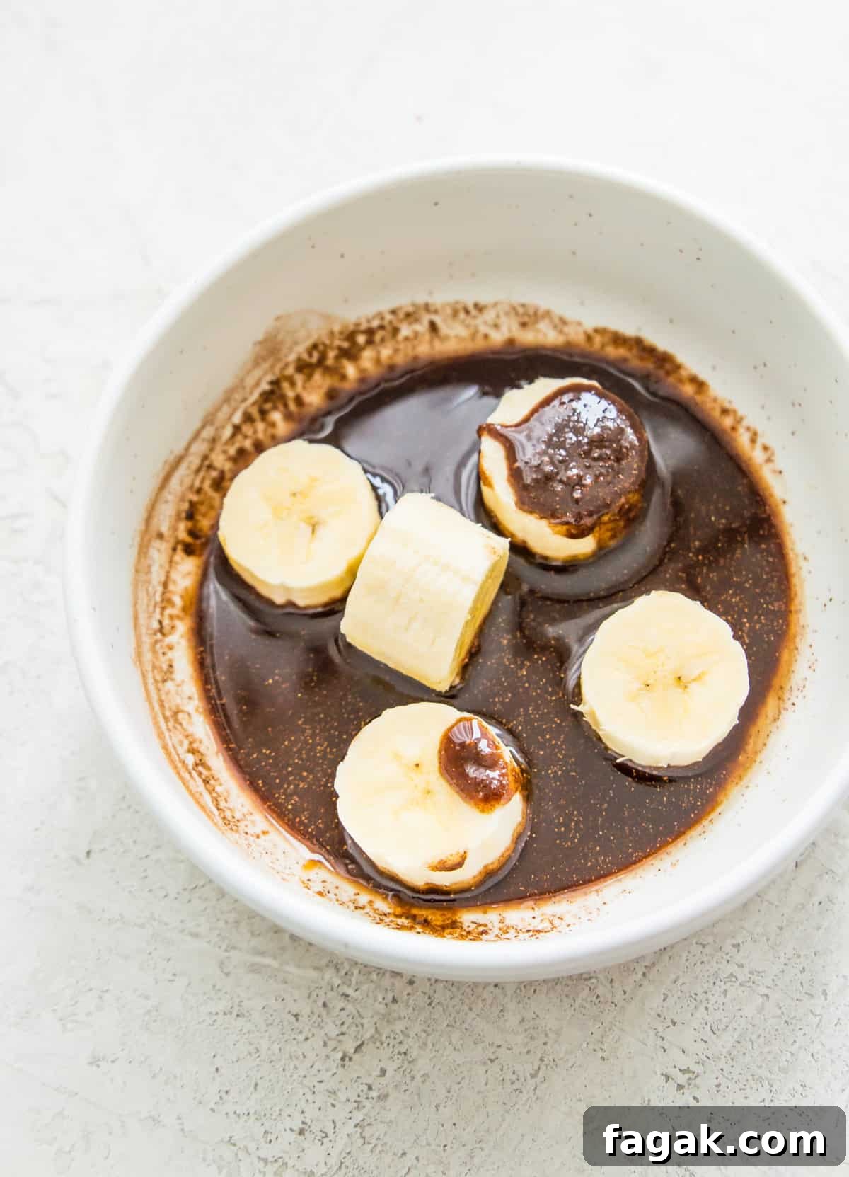 Caramelized Cinnamon Bananas in the Air Fryer 6 Banana slices in a bowl with a cinnamon sugar mixture coating them.