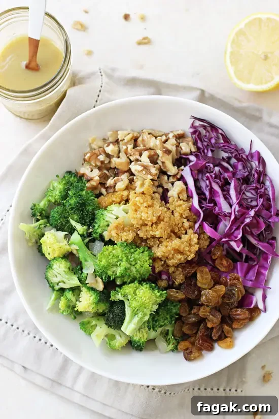 Overhead view of Crunchy Broccoli Quinoa Salad in a bowl with dressing and a lemon to the side.
