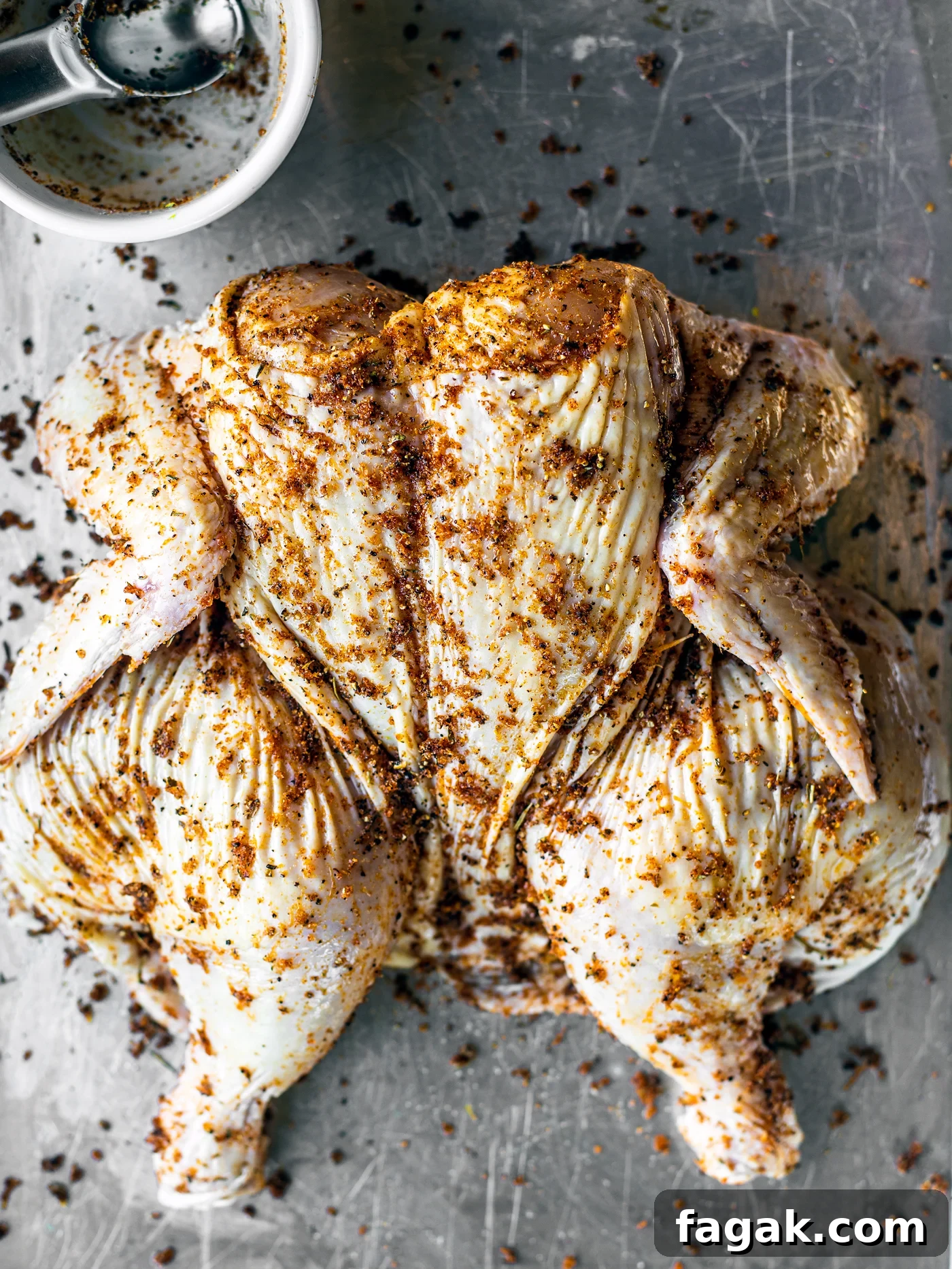 Spatchcocked chicken on a baking sheet.