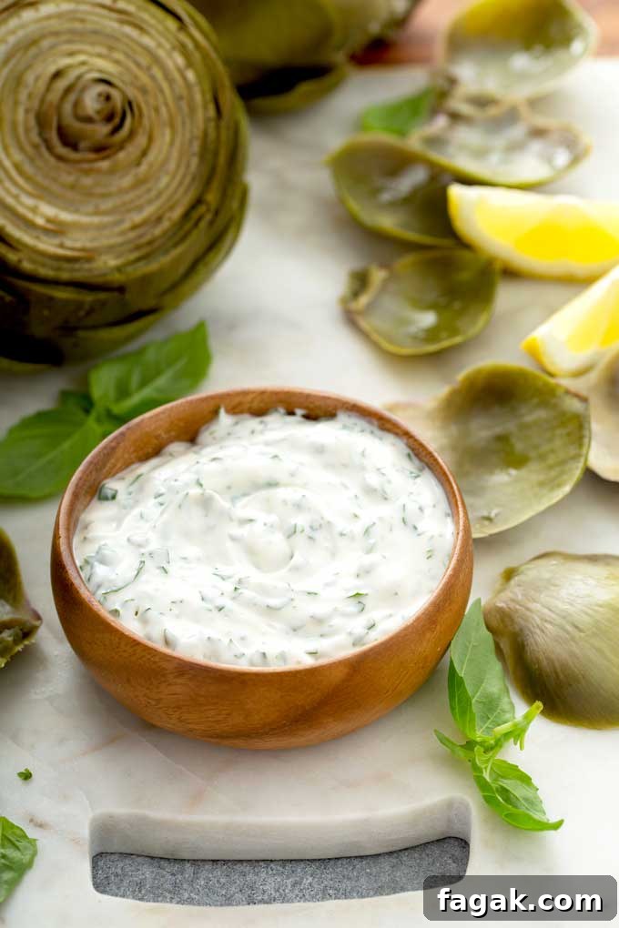 Creamy dipping sauce in a wooden bowl around artichoke leaves