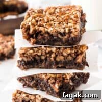 pecan pie brownies stacked between pieces of parchment paper
