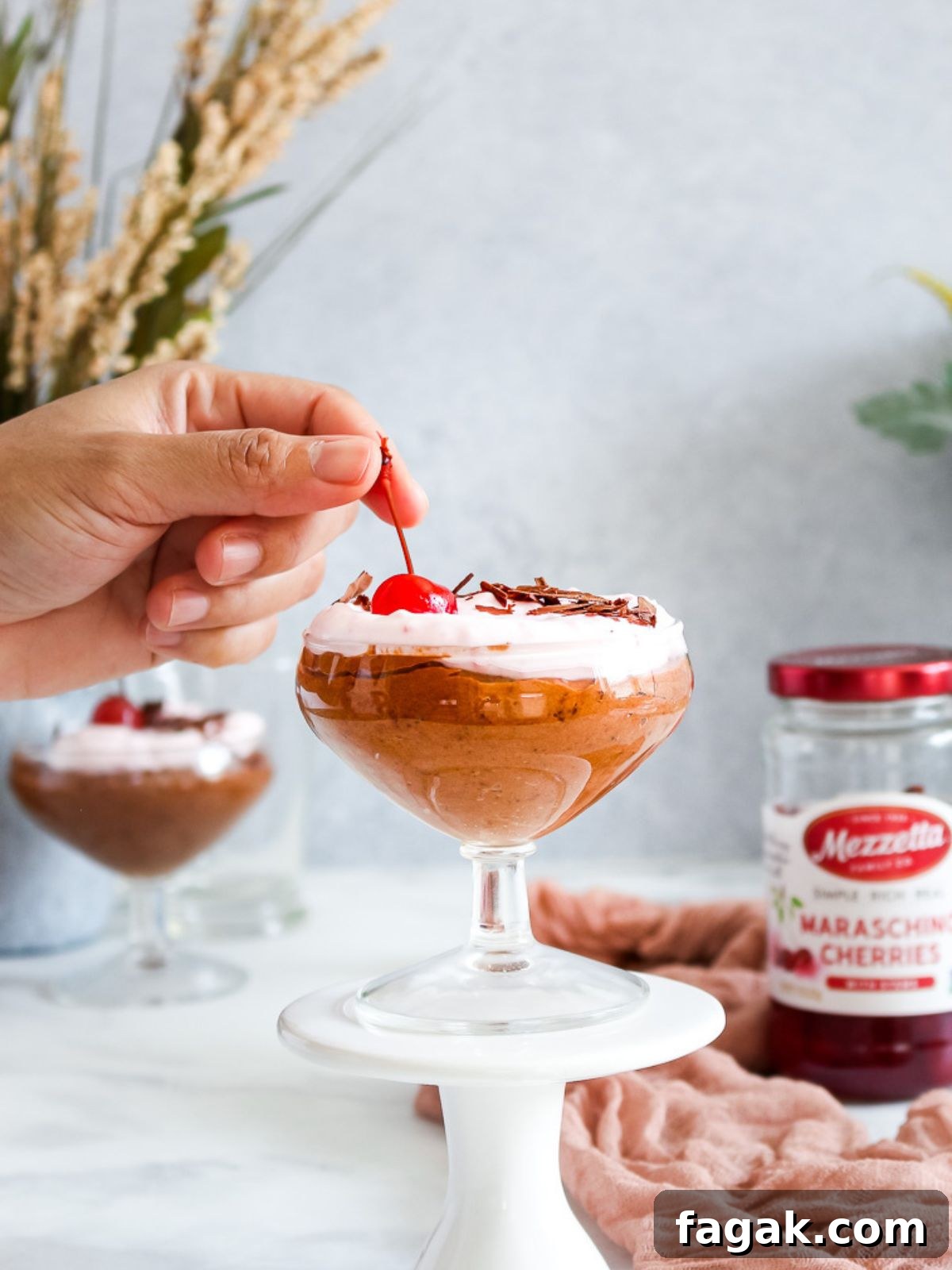 topping the chocolate mousse with maraschino cherries.