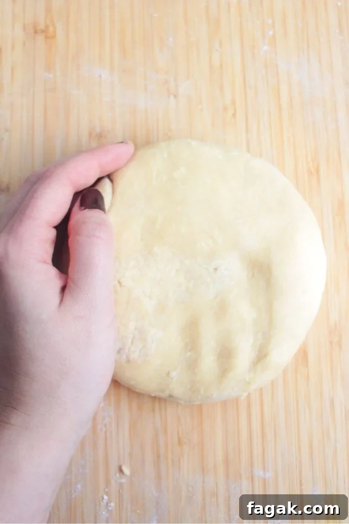 Hand forming a pastry circle on a wooden background.