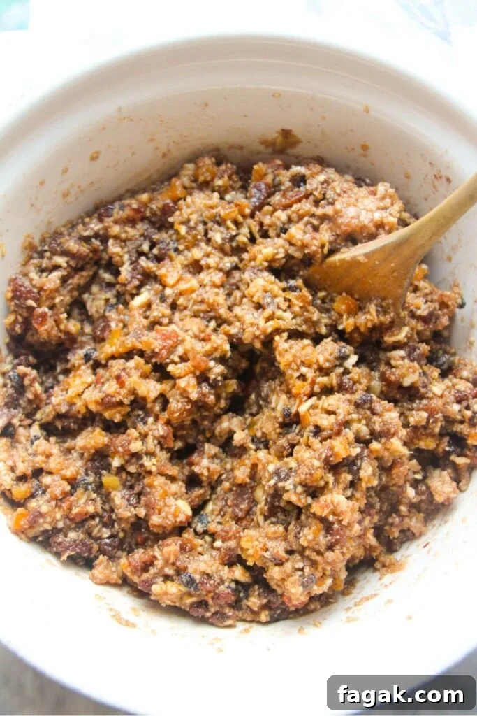 Christmas fruit mince in a large white bowl with a wooden spoon in the bowl.