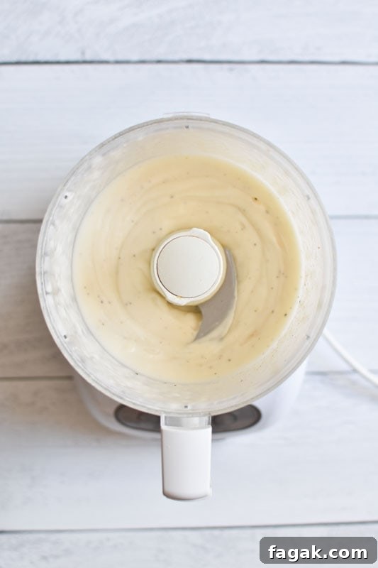 Whipped mayo in a food processor on a white board