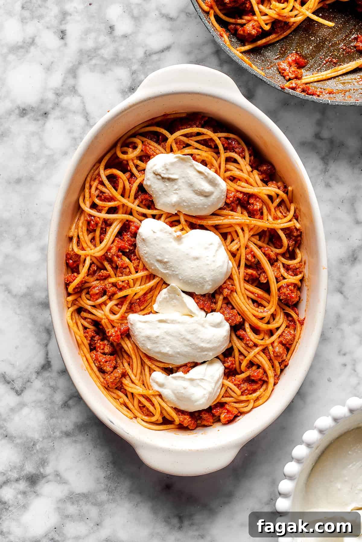 Adding cheese mixture on top of spaghetti.