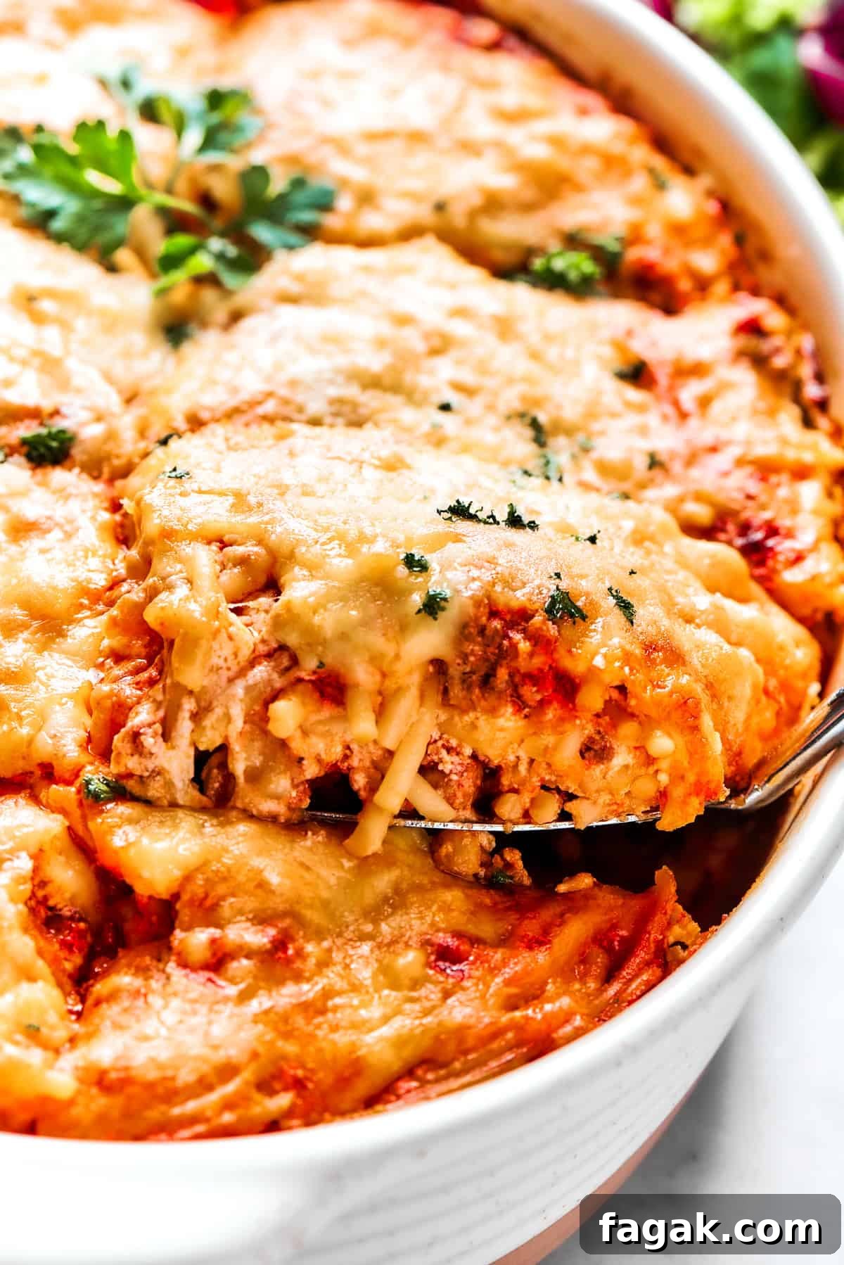 Spooning out baked spaghetti from a casserole dish.