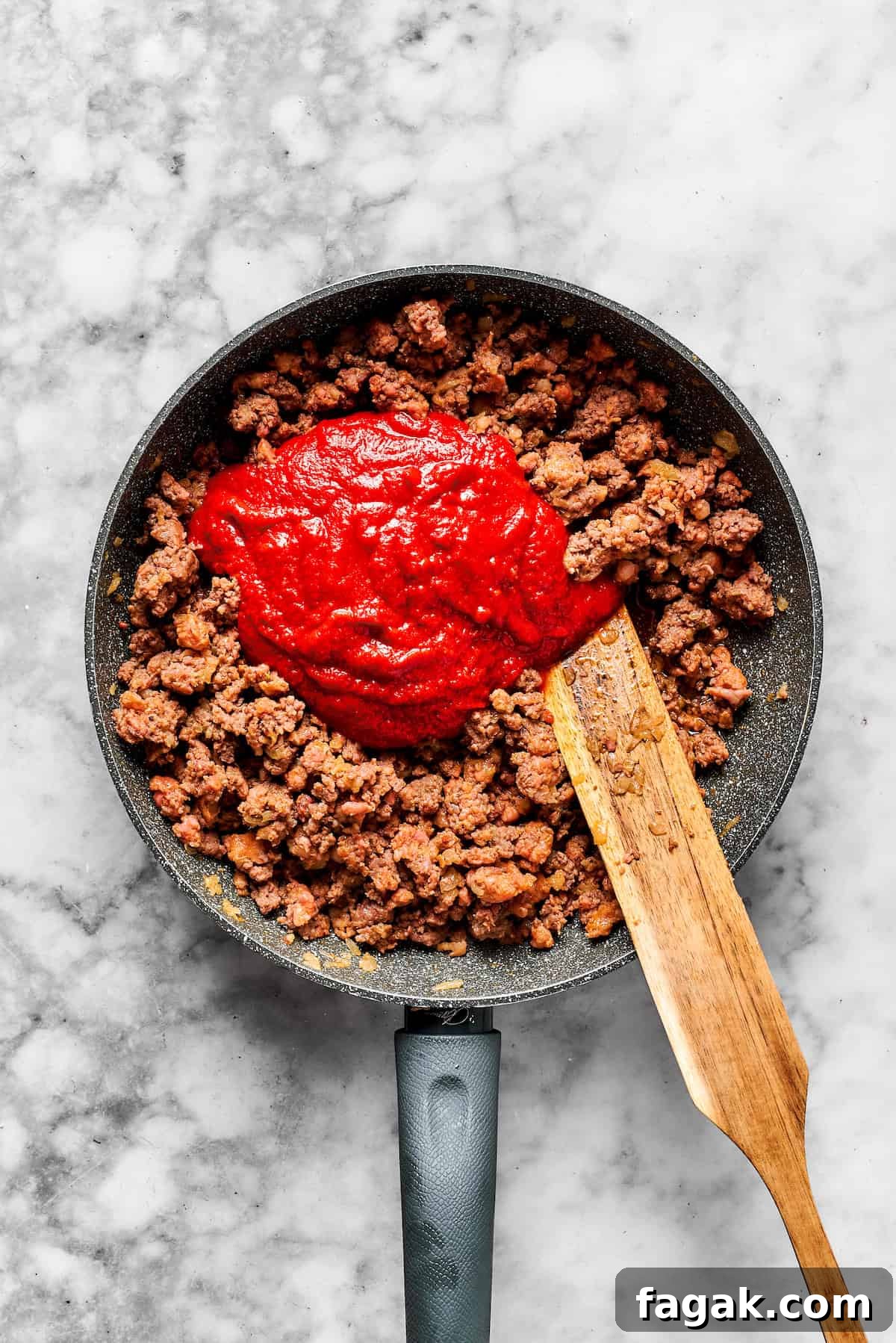 Adding pasta sauce to a skillet with cooked meat.