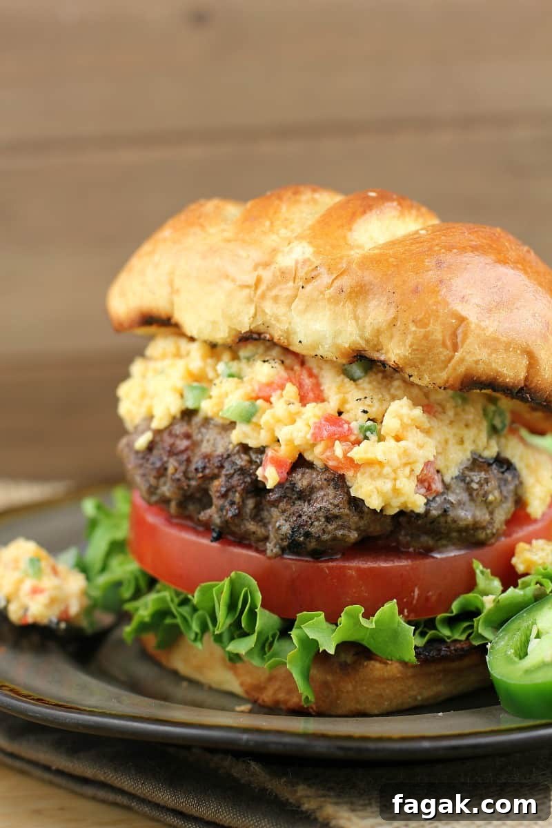 cheeseburger in a bun with lettuce, tomato, and pimento cheese