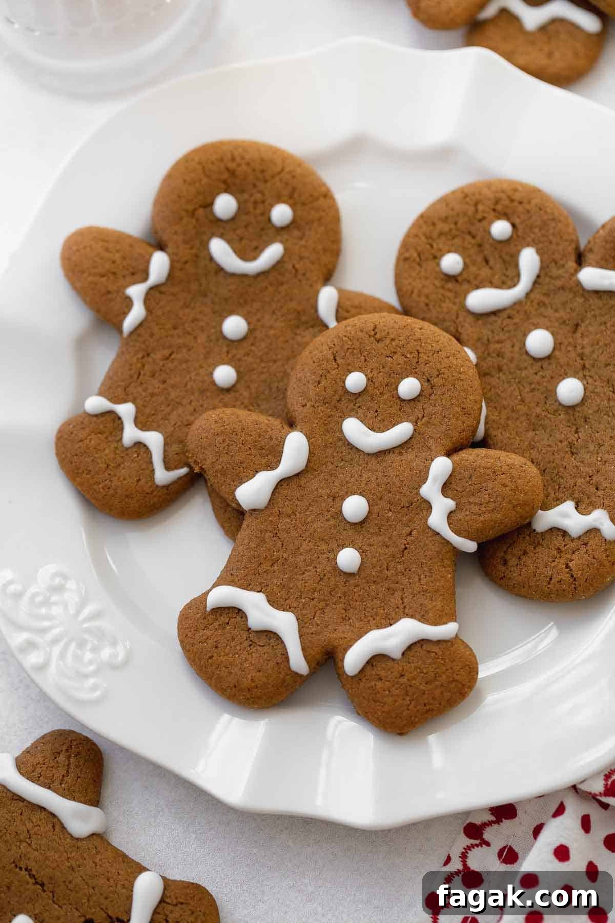 close up of gluten free gingerbread cookies on white plate with glass of milk.