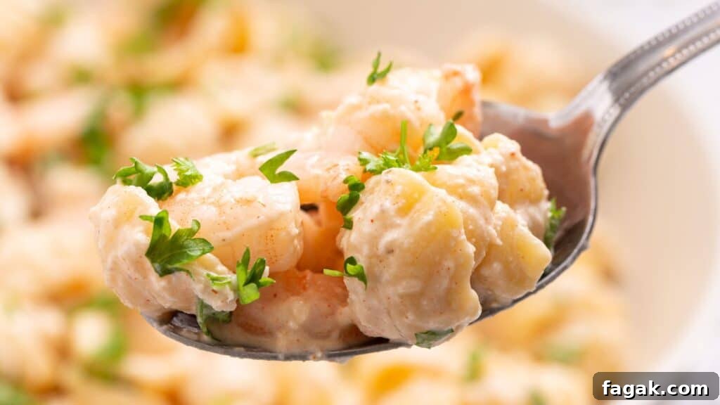 16 Light and Satisfying Shrimp Recipes for Quick Weeknight Meals 2 Close-up of a spoon holding seafood pasta salad garnished with parsley, with more salad in the background.