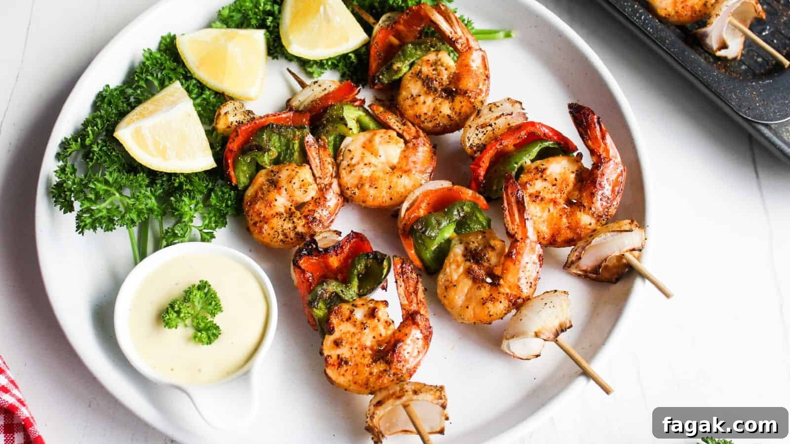 16 Light and Satisfying Shrimp Recipes for Quick Weeknight Meals 4 Grilled shrimp skewers with red and green bell peppers, served with lemon wedges and a dipping sauce on a white plate.
