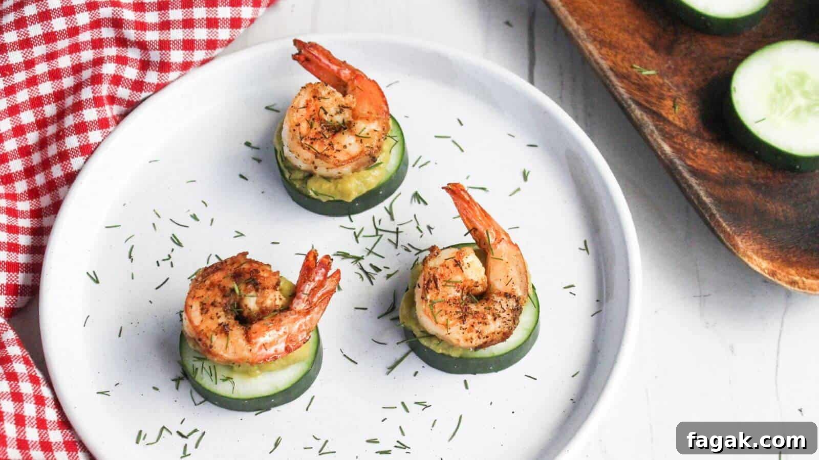 16 Light and Satisfying Shrimp Recipes for Quick Weeknight Meals 8 Three grilled shrimp atop cucumber slices garnished with herbs on a white plate with a red checkered napkin partially in view.