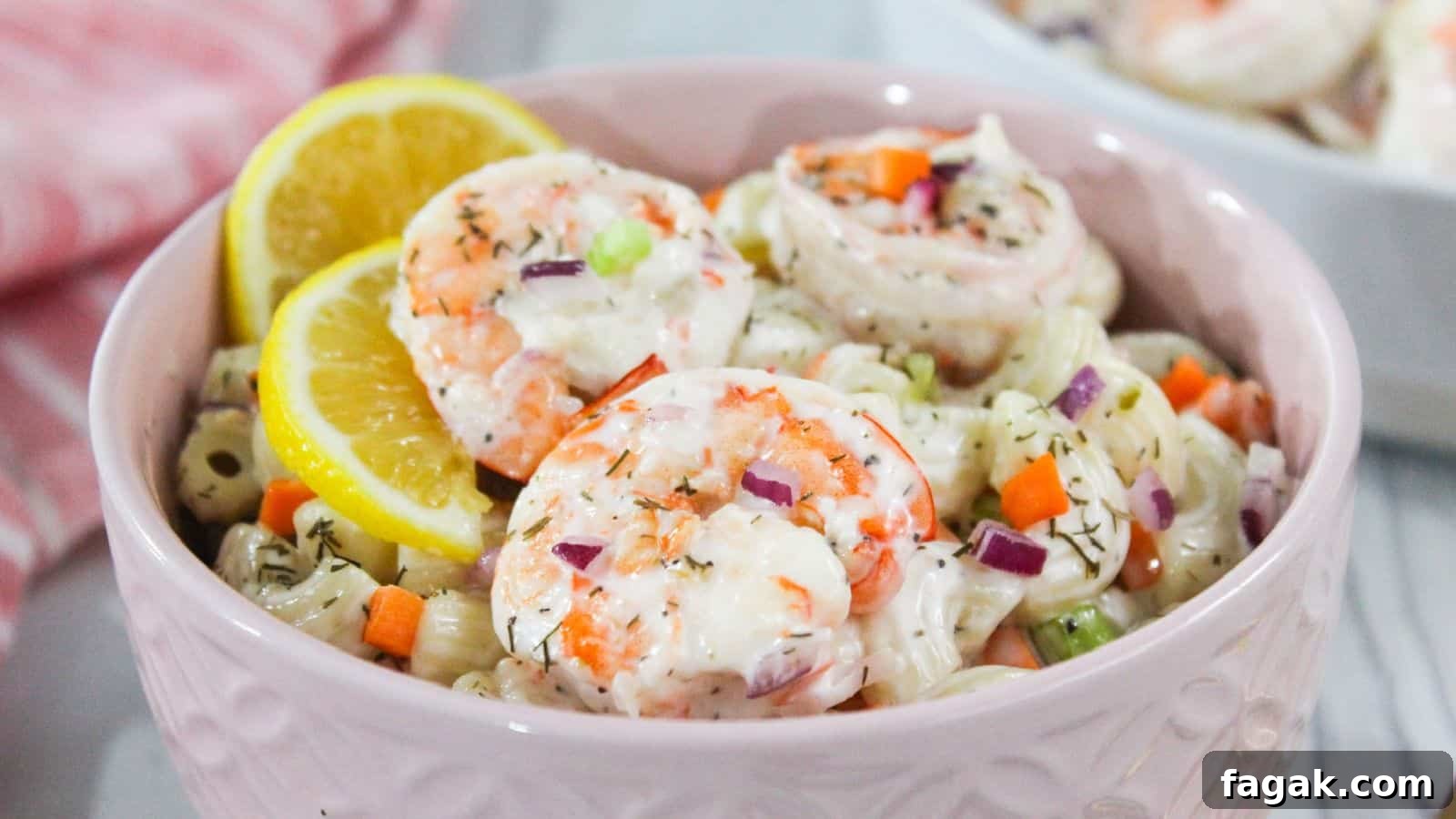 16 Light and Satisfying Shrimp Recipes for Quick Weeknight Meals 10 Shrimp macaroni salad in a pink bowl with lemon wedges.