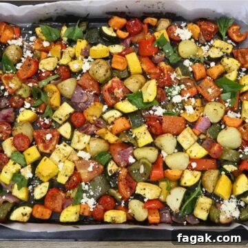 mediterranean oven roasted vegetables in a baking sheet. Garnished with Feta cheese and basil leaves.
