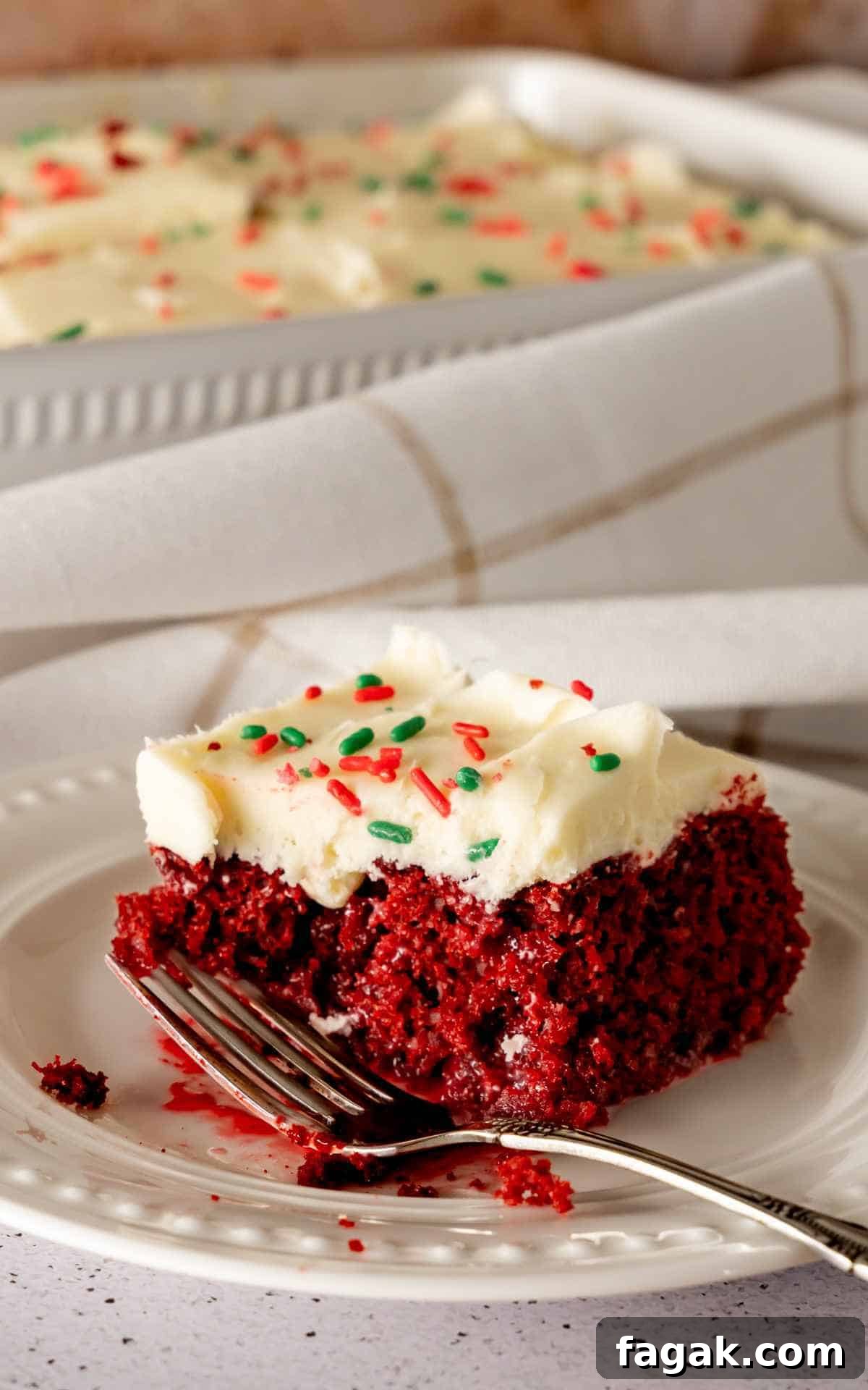 A slice of red velvet poke cake topped with cream cheese frosting.