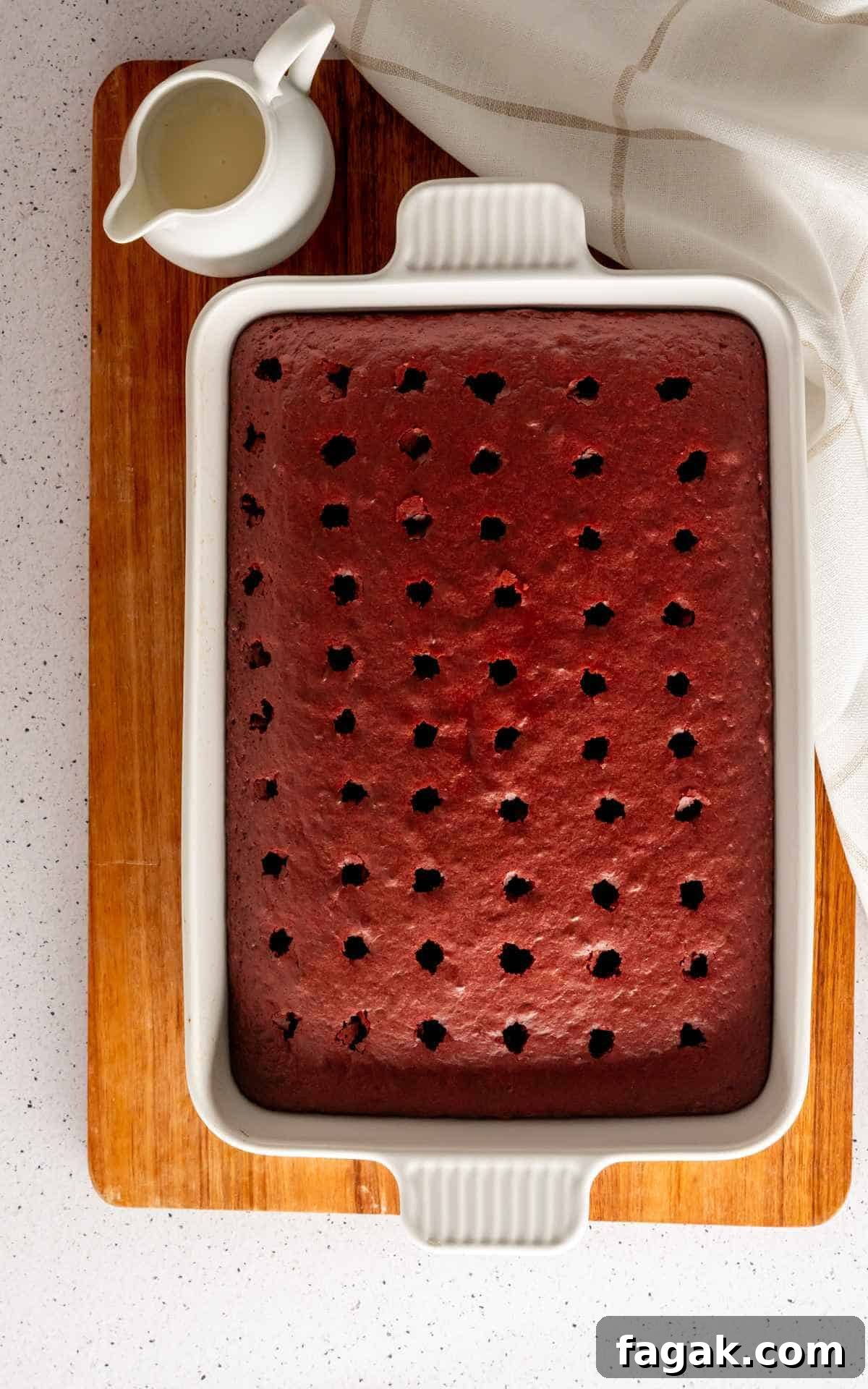 Red Velvet Cake with holes poked in it to make poke cake.