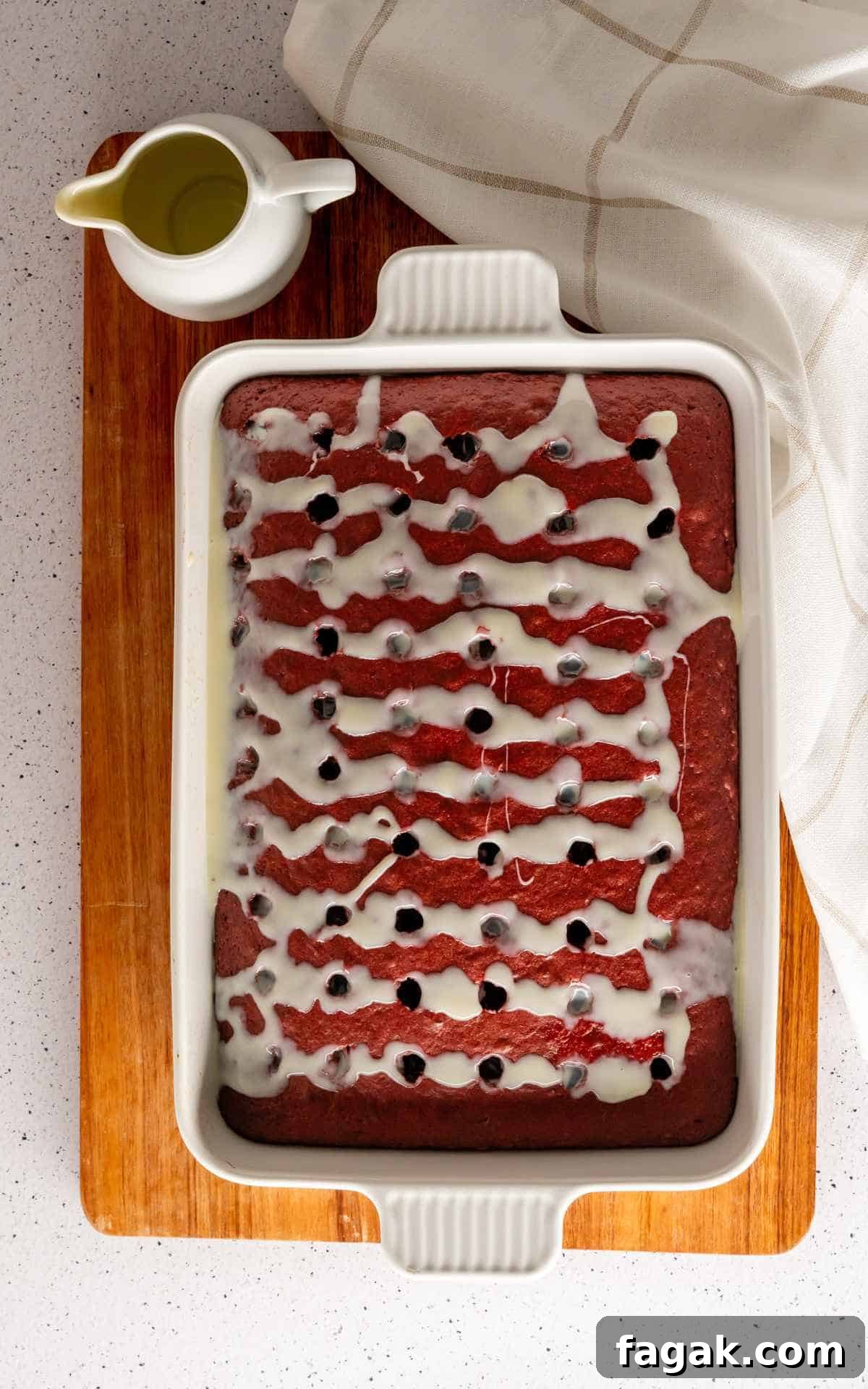 Sweetened condensed milk poured into the holes of the red velvet poke cake.