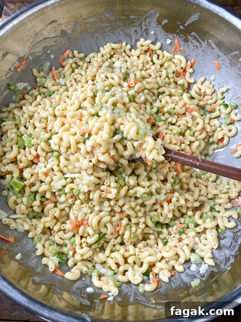 Long handled wooden spoon stirring a big batch of easy macaroni salad